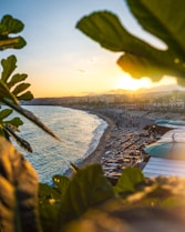 the sun is setting over a beach with surfboards