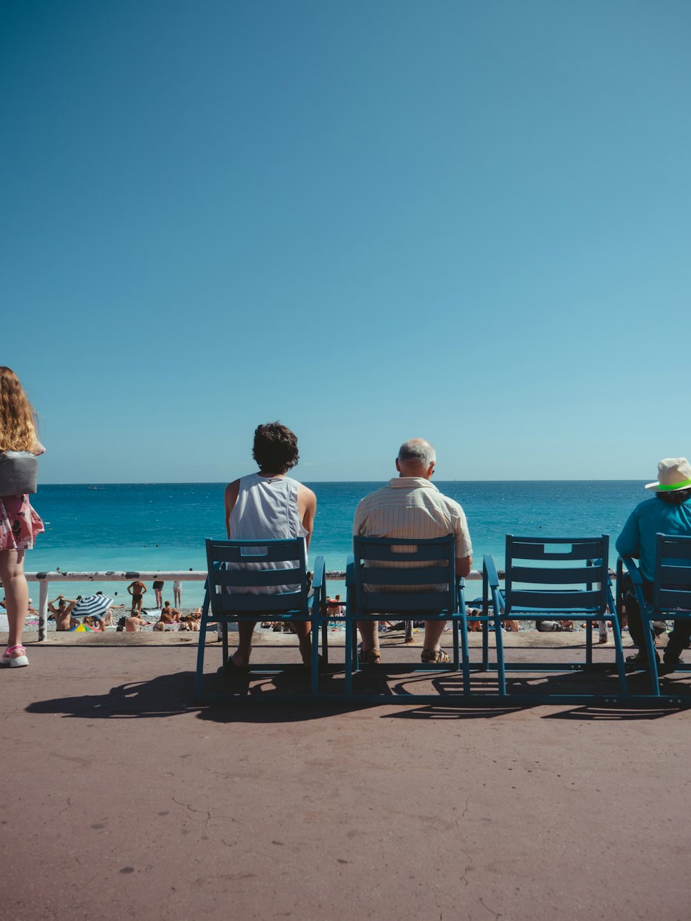 Eine Gruppe von Menschen, die auf einem Strand neben dem Meer sitzen