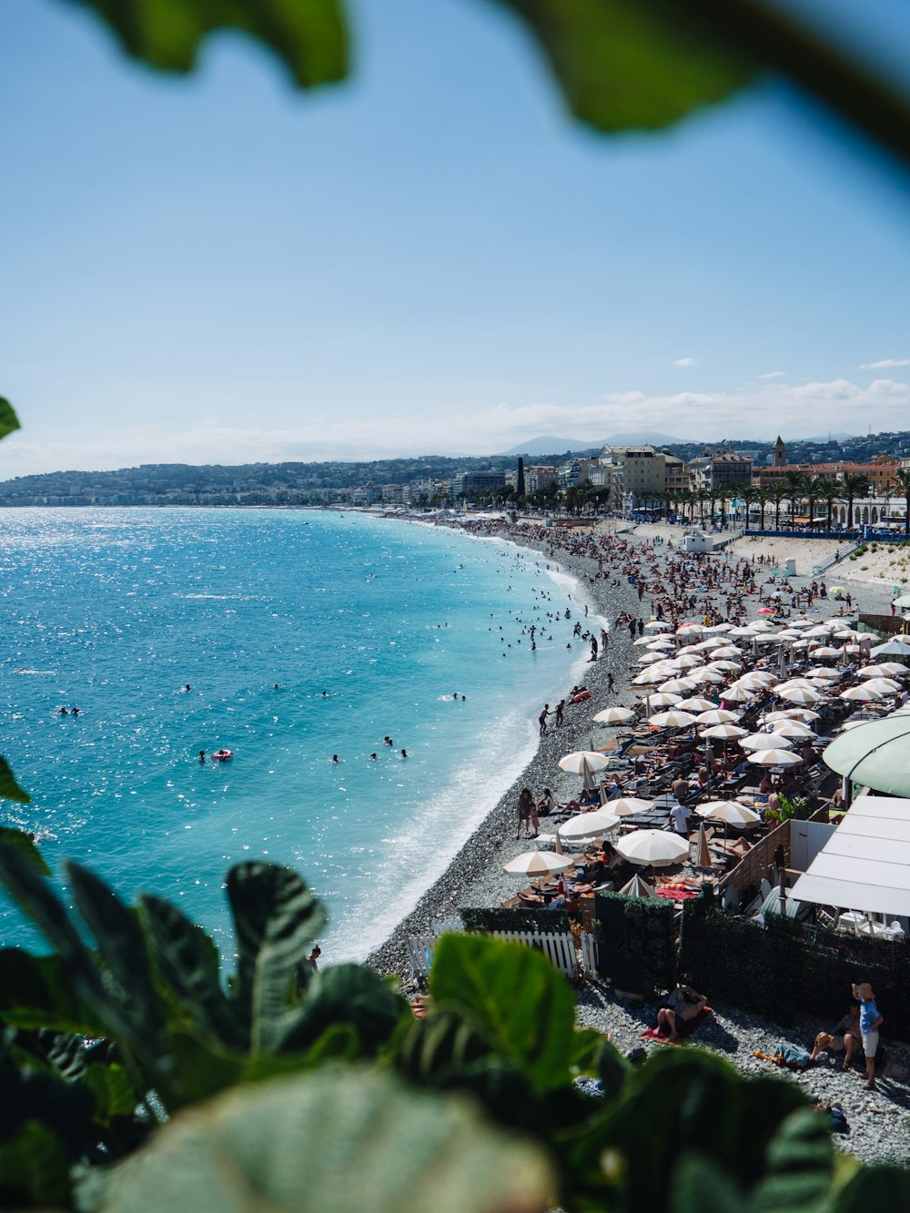 a crowded beach with umbrellas and people in the water