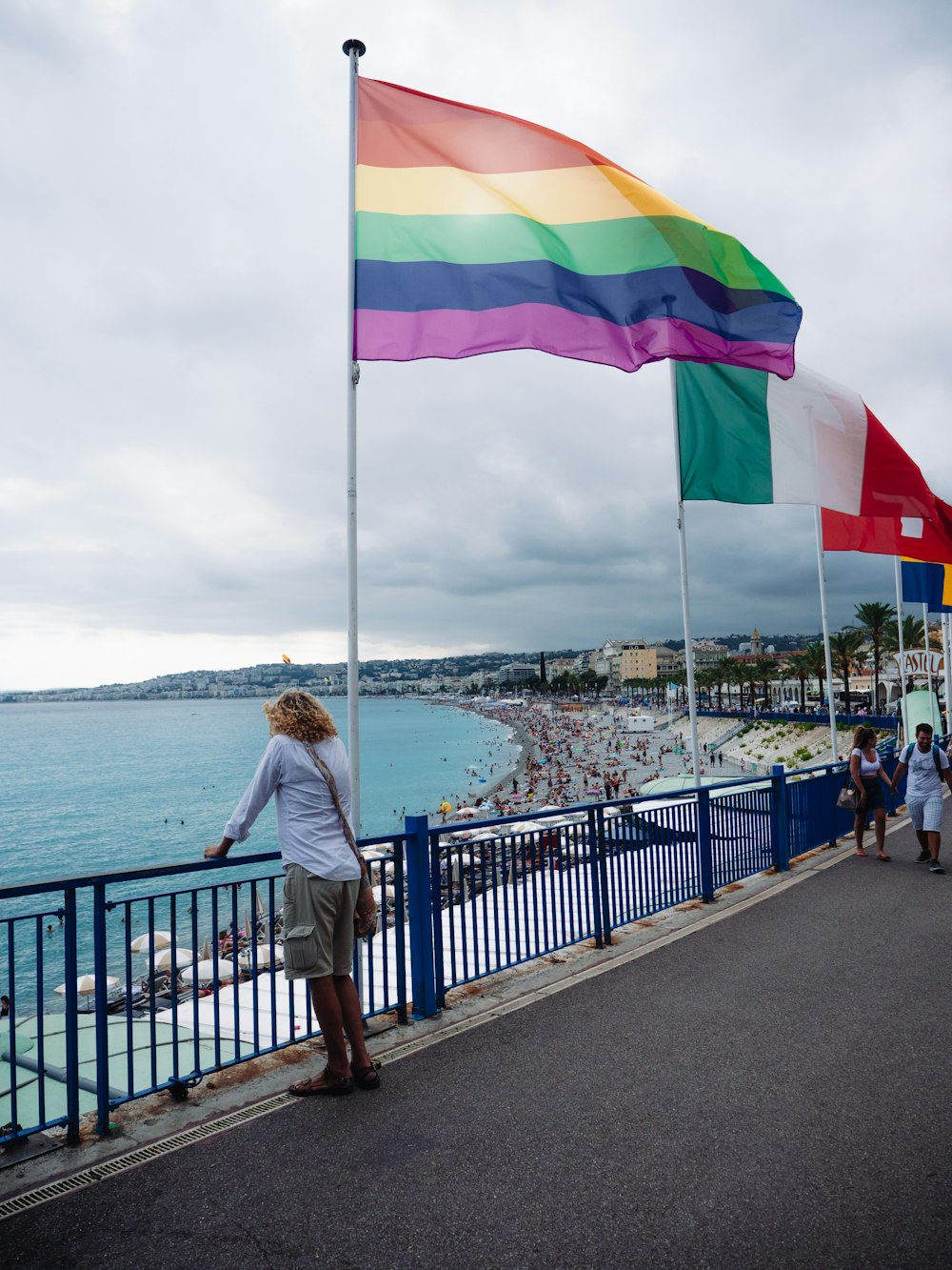 a woman standing next to a rainbow flag