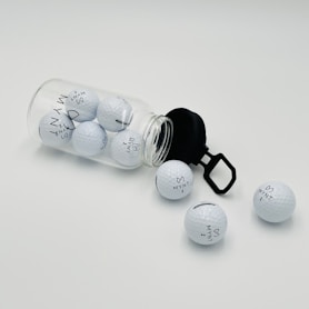 a glass jar filled with golf balls on top of a white table