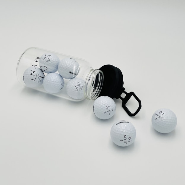 a glass jar filled with golf balls on top of a white table