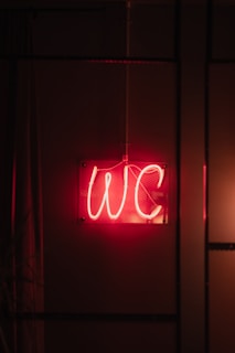 a red neon sign hanging from the side of a wall