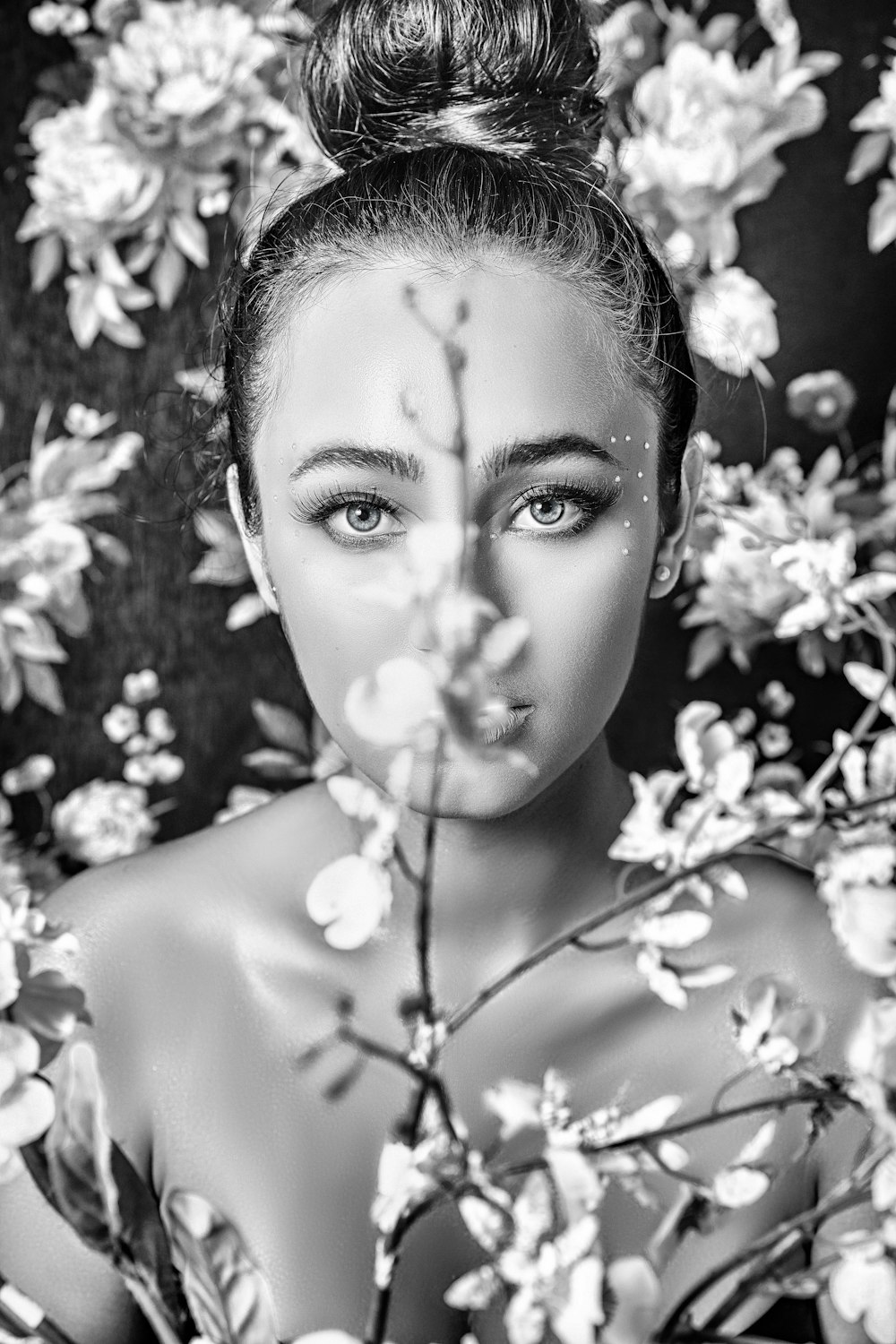 a black and white photo of a woman surrounded by flowers