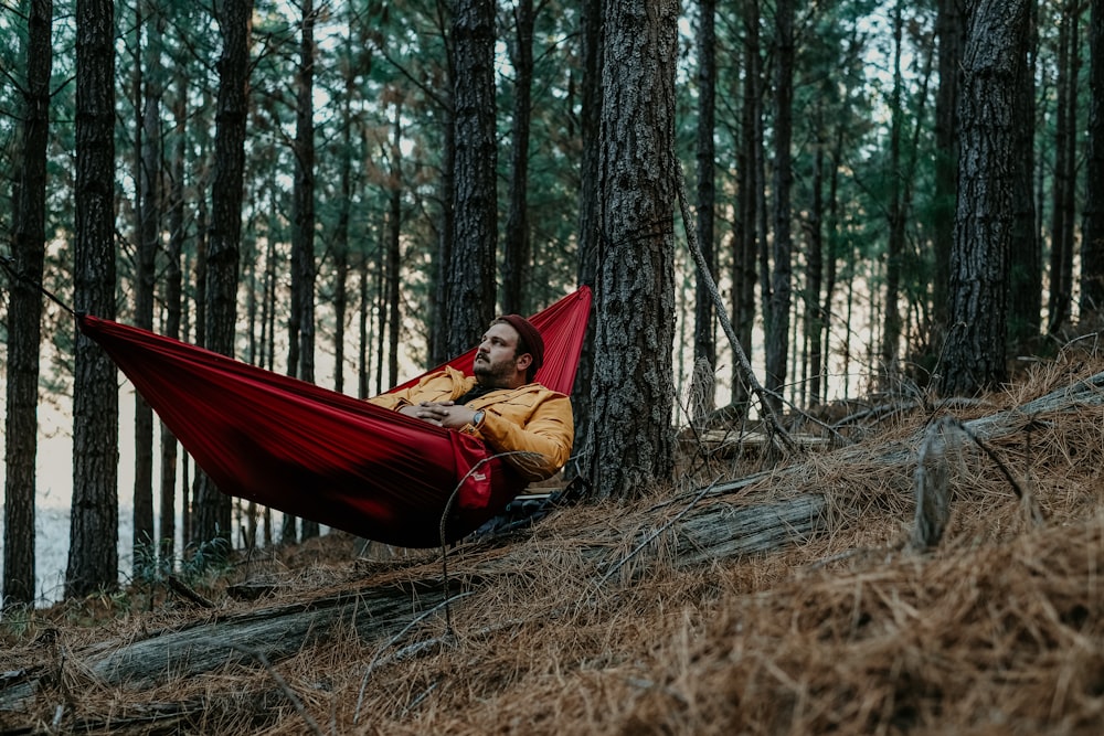 a man laying in a hammock in the woods