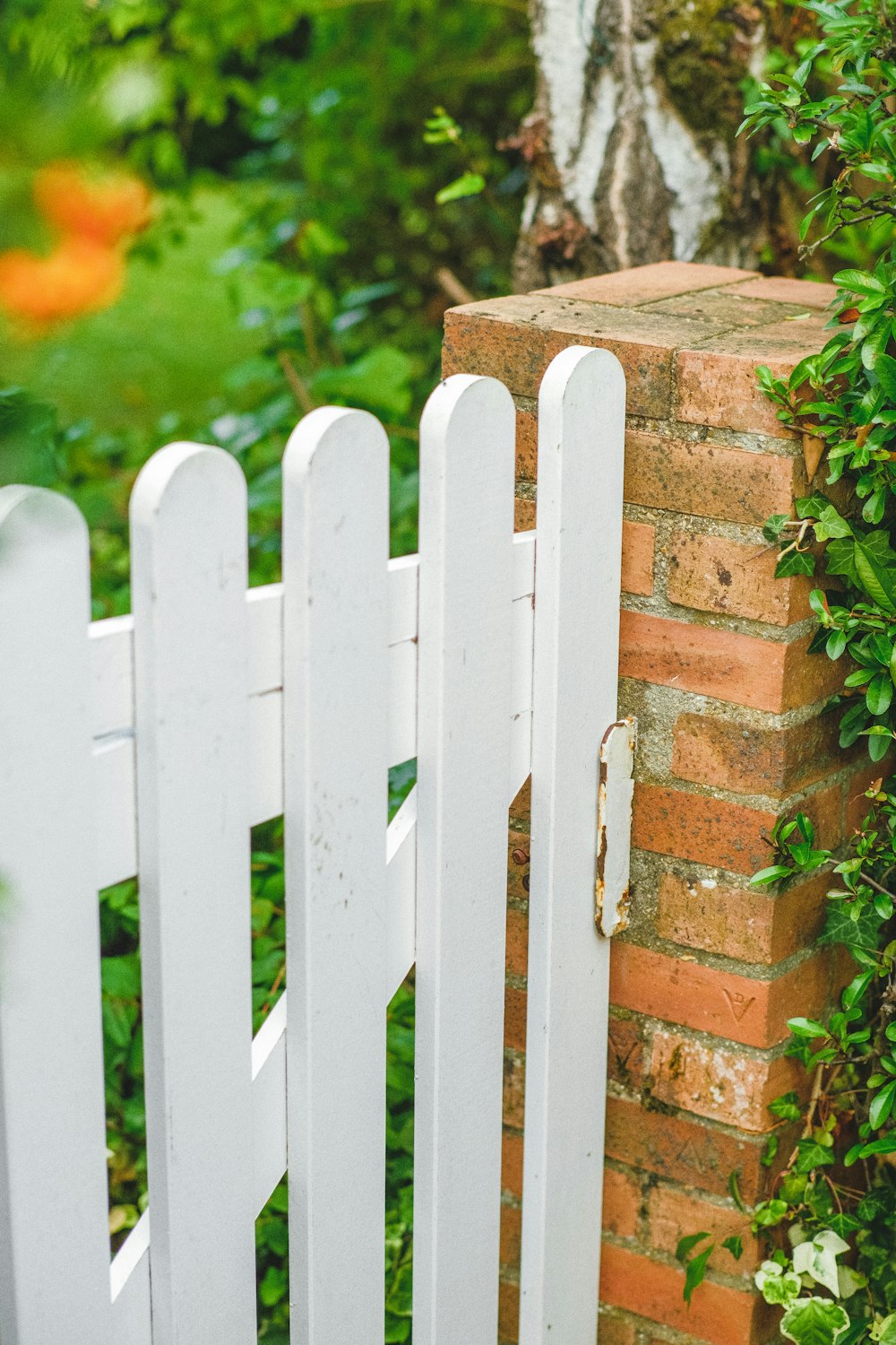 a white picket fence next to a brick wall