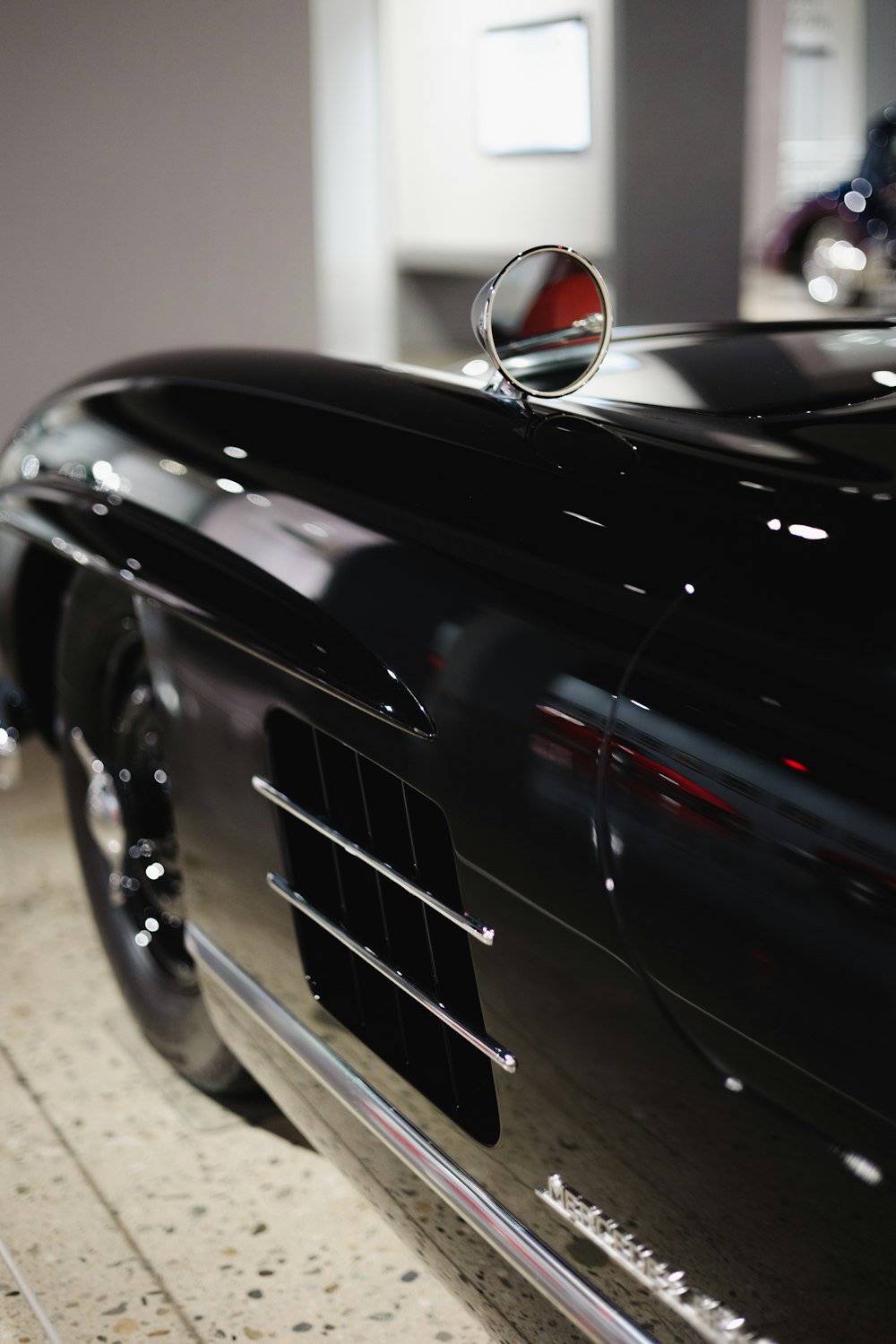 a black car parked in a garage next to another car