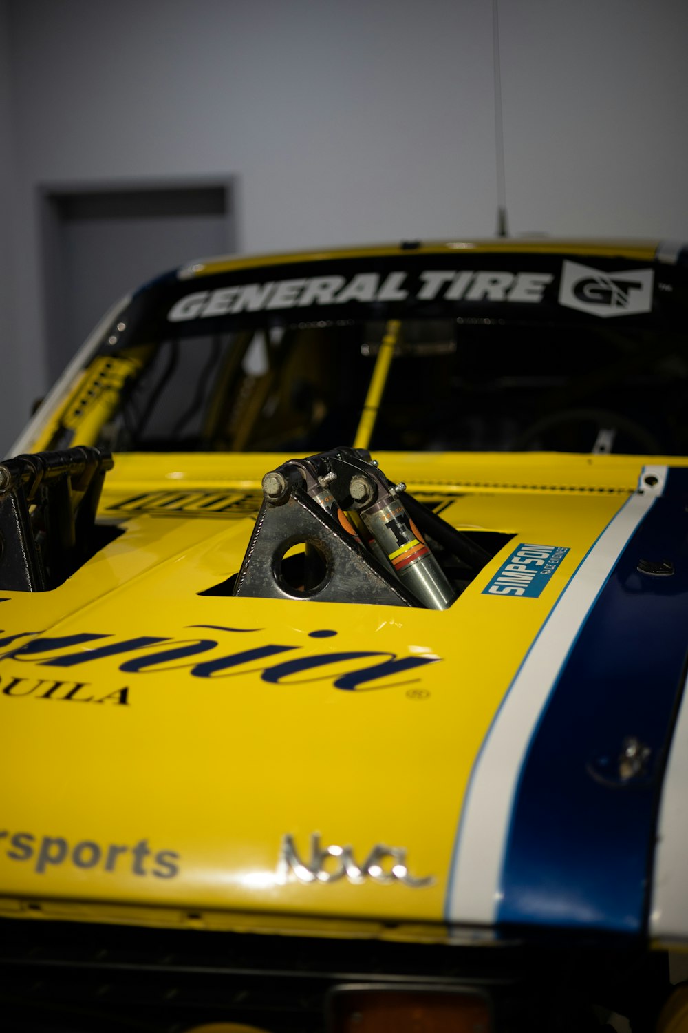a close up of a yellow race car with blue and white stripes