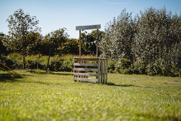 a wooden sign sitting on top of a lush green field