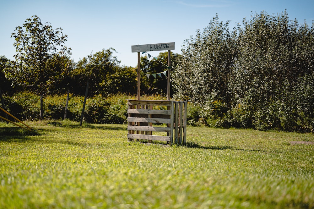a wooden sign sitting on top of a lush green field