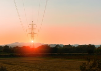 the sun is setting behind a power line