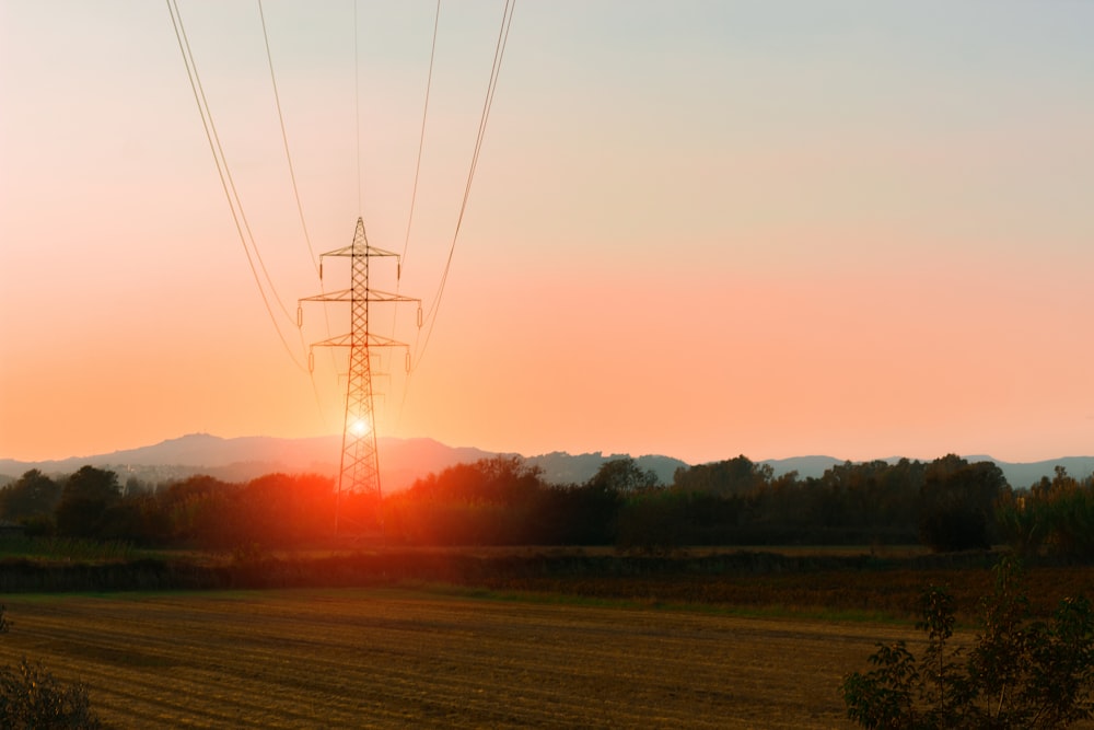 the sun is setting behind a power line