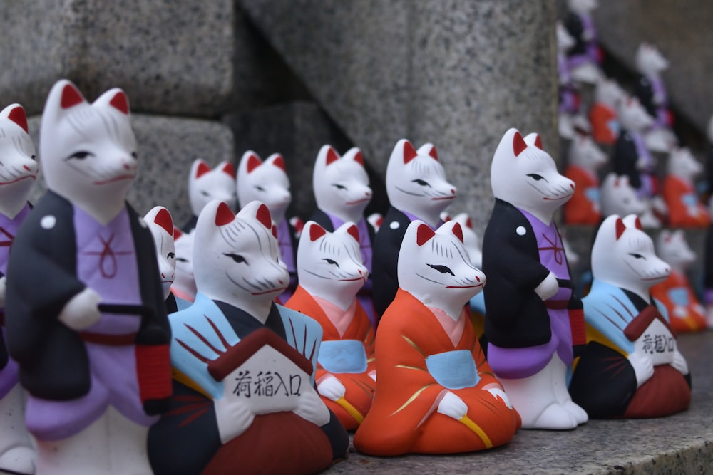 Un grupo de pequeñas figuritas de gatos sentados en una repisa