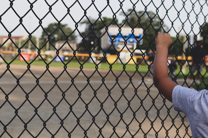 Youth baseball player at the plate behind a chain-link fence