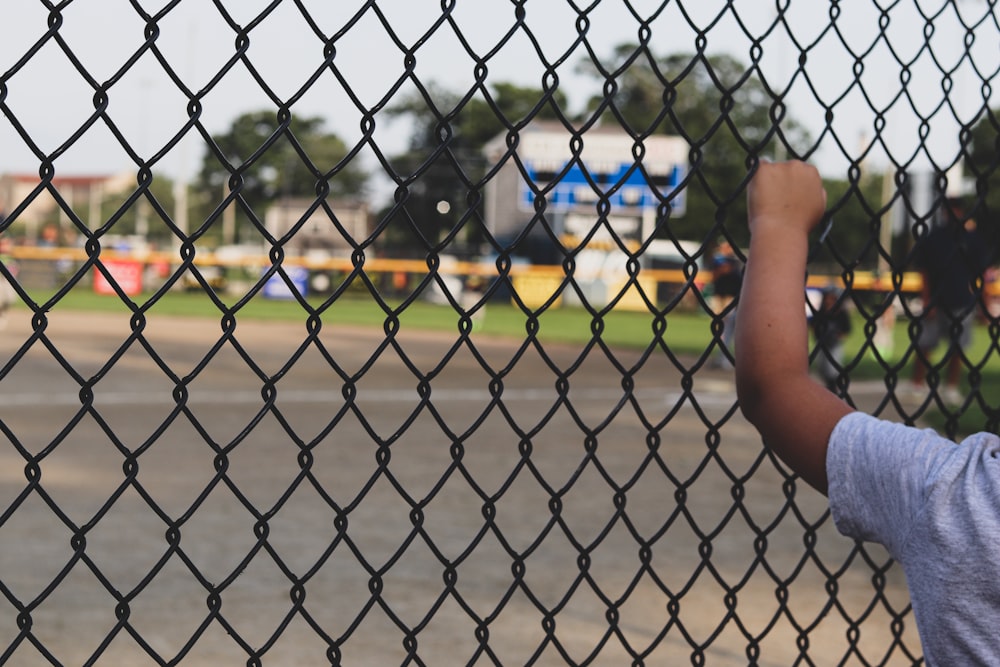 a young boy holding a baseball bat behind a fence