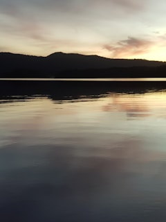 A calm lake reflecting a pastel-colored sky during early evening.