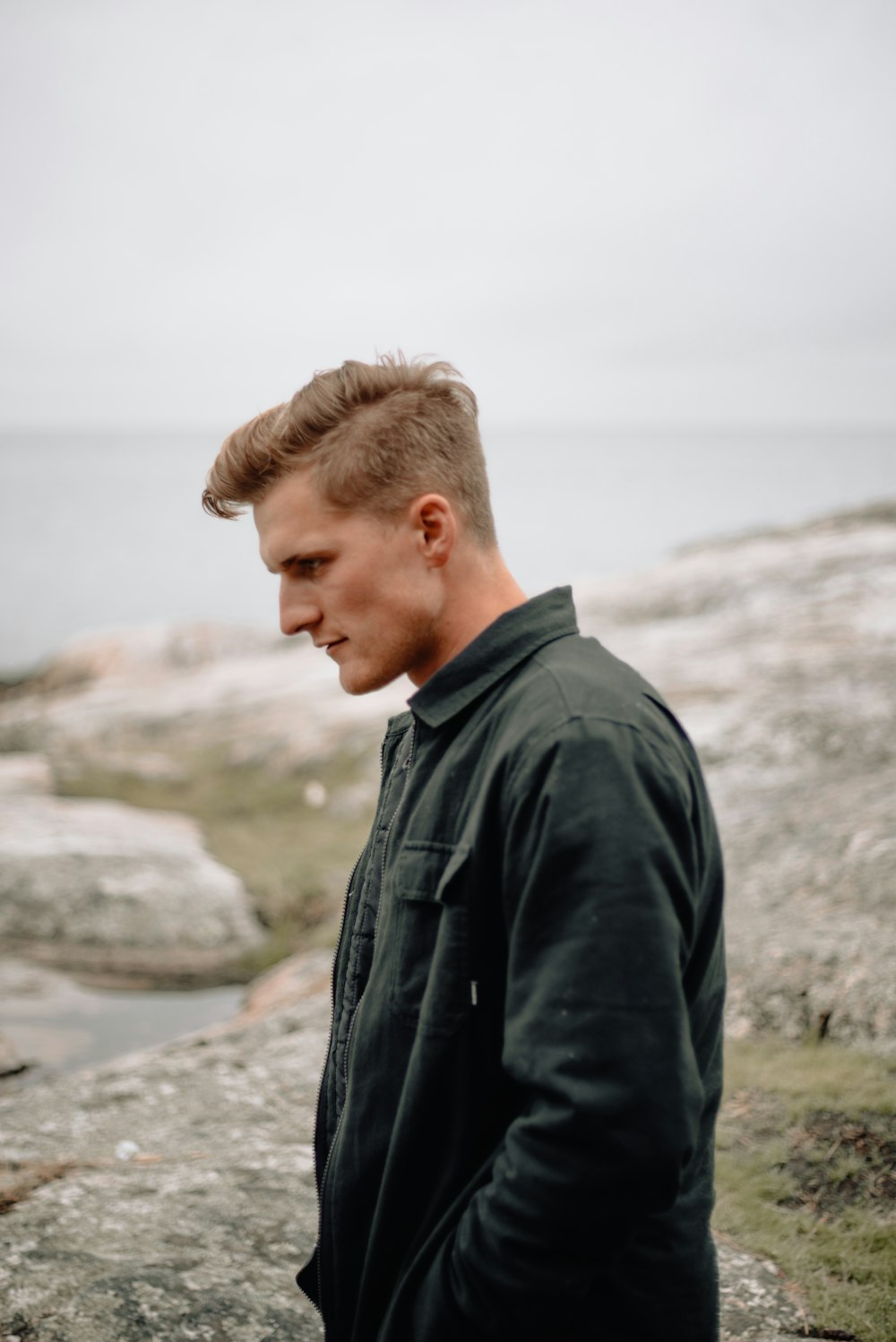 a man standing on top of a rocky beach next to the ocean