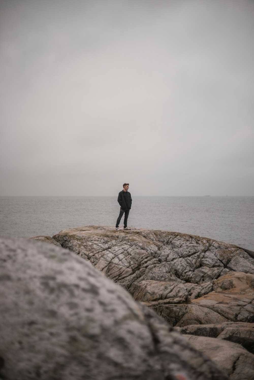 a man standing on top of a rock near the ocean