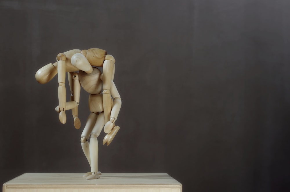 Una escultura de madera de una persona sosteniendo un objeto de madera
