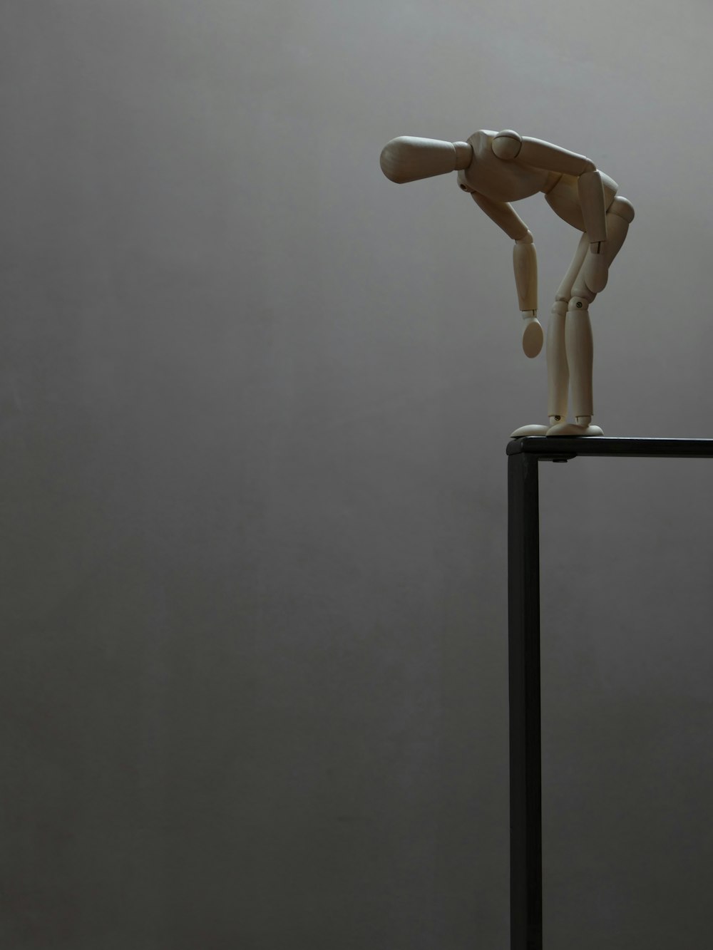 a wooden mannequin standing on top of a metal pole