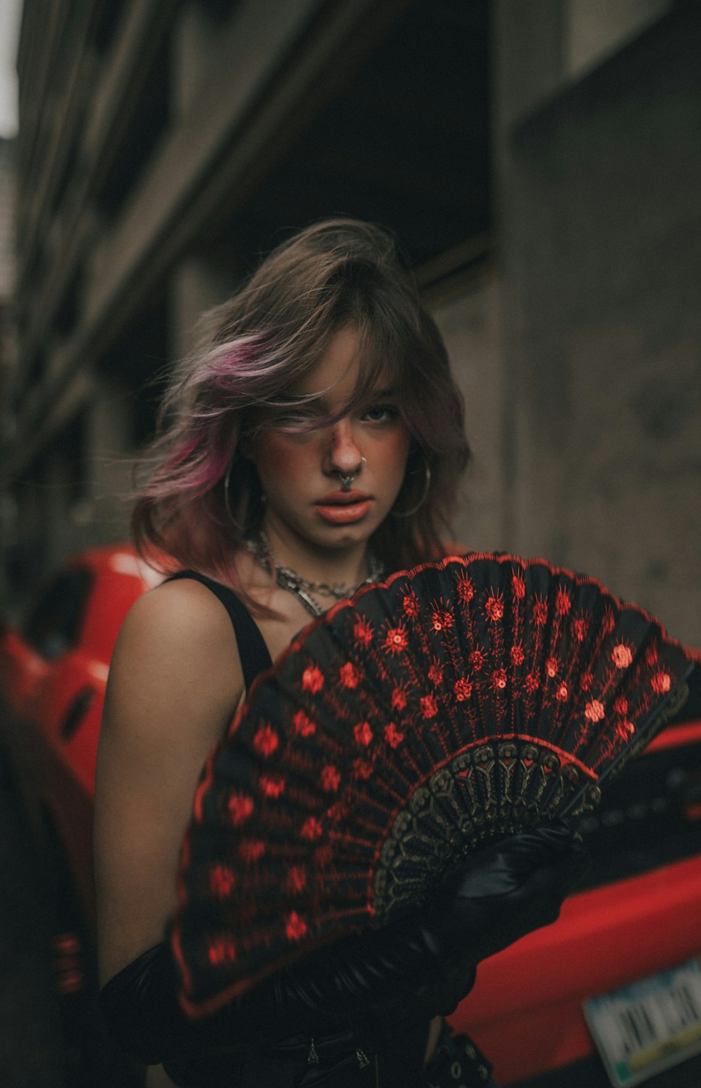a woman with pink hair holding a red and black fan