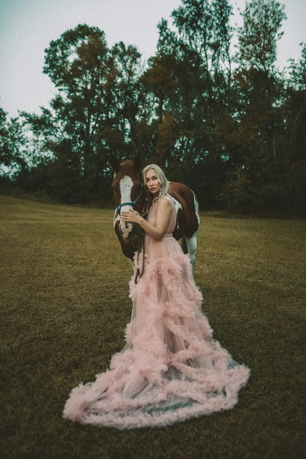 a woman in a pink dress standing next to a horse