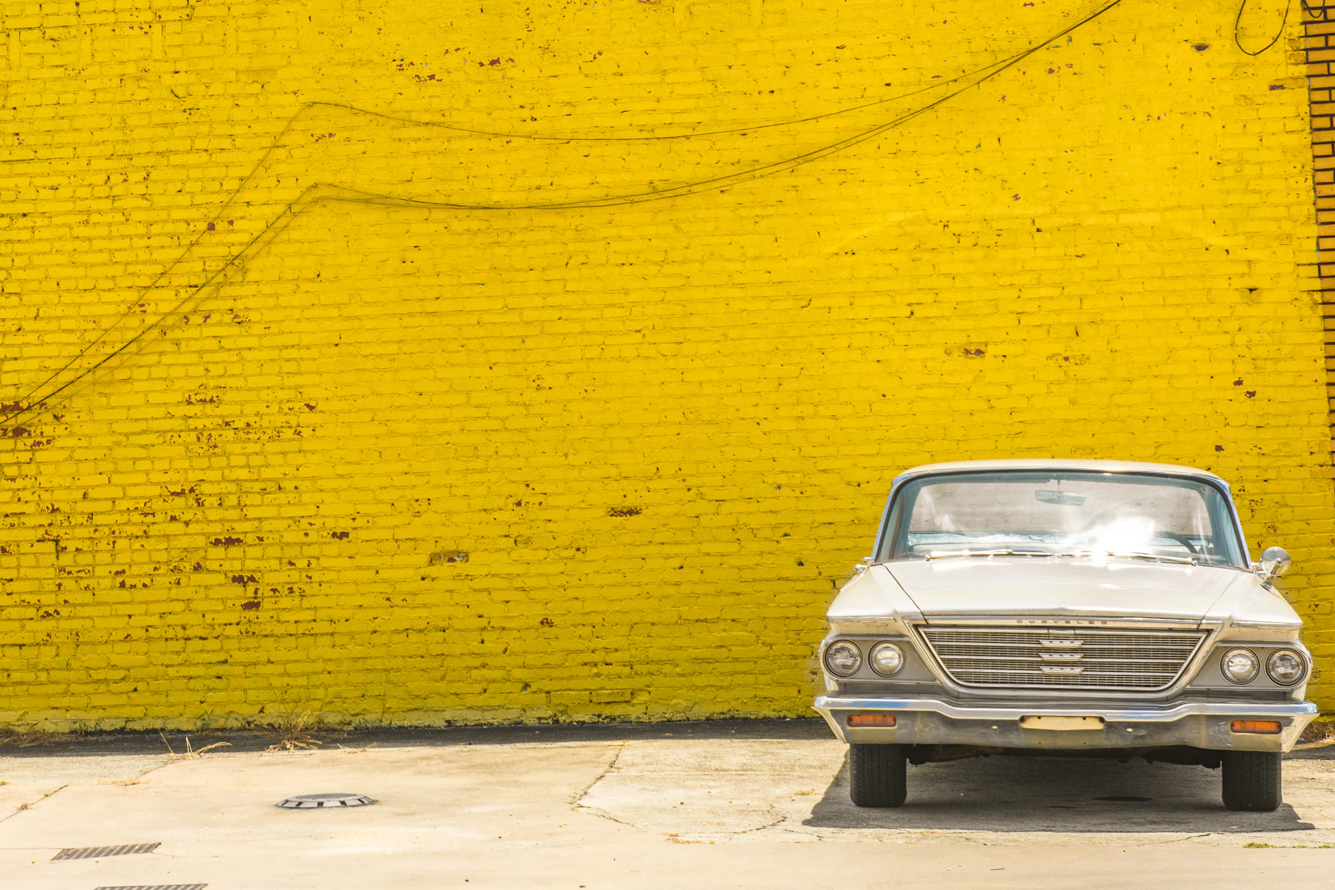 a white car parked in front of a yellow brick wall