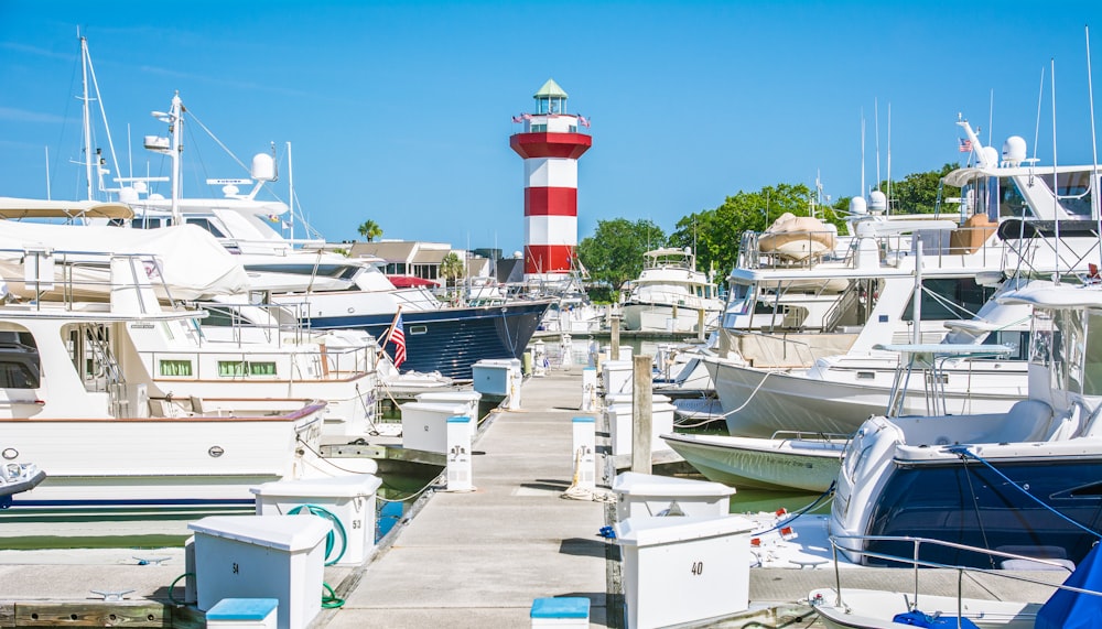 a dock with boats and a lighthouse in the background