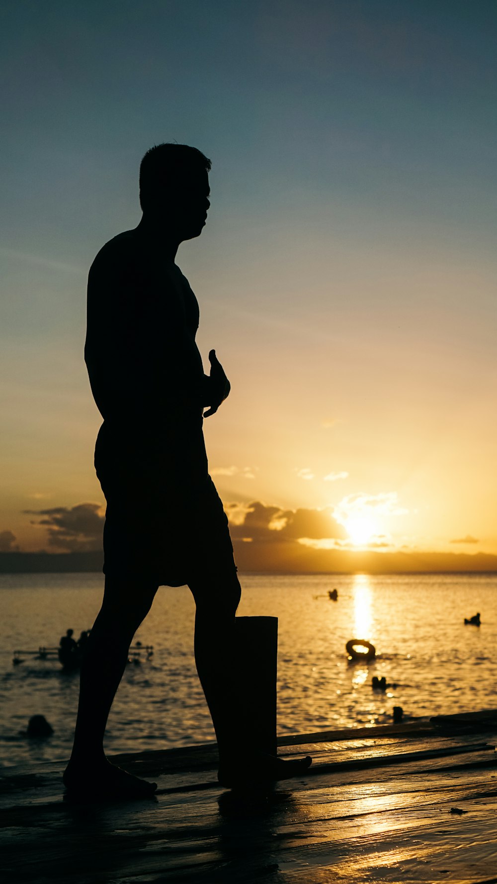 a silhouette of a man walking on a pier at sunset
