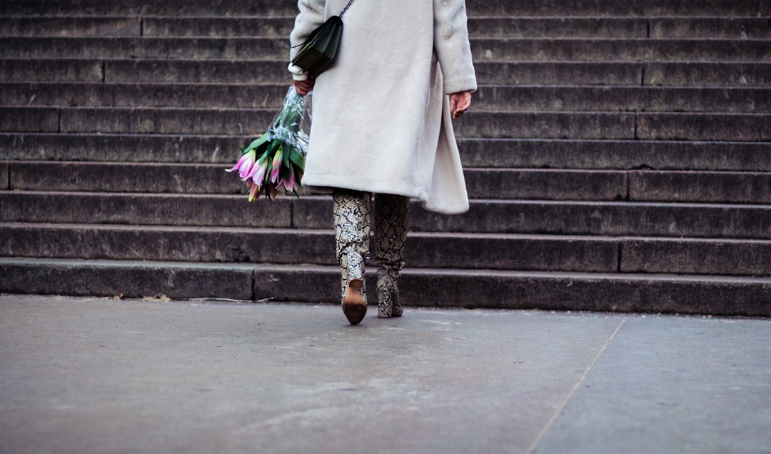 a woman walking down a street holding a bunch of flowers