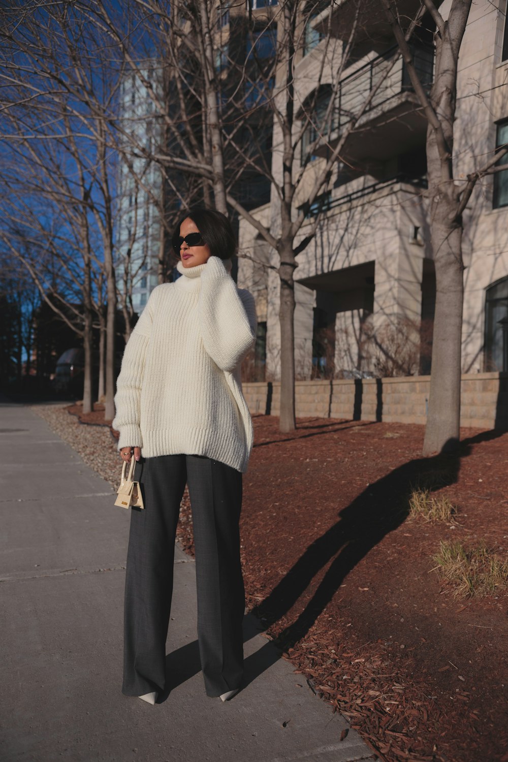 a woman standing on a sidewalk in front of a building