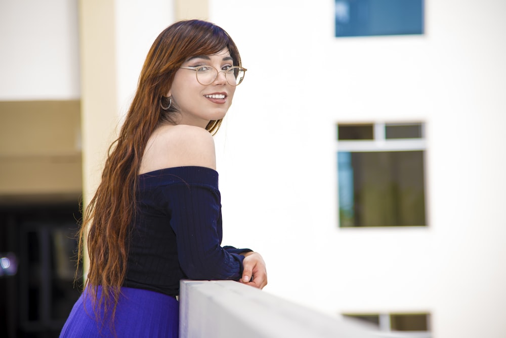 a woman with glasses leaning on a wall