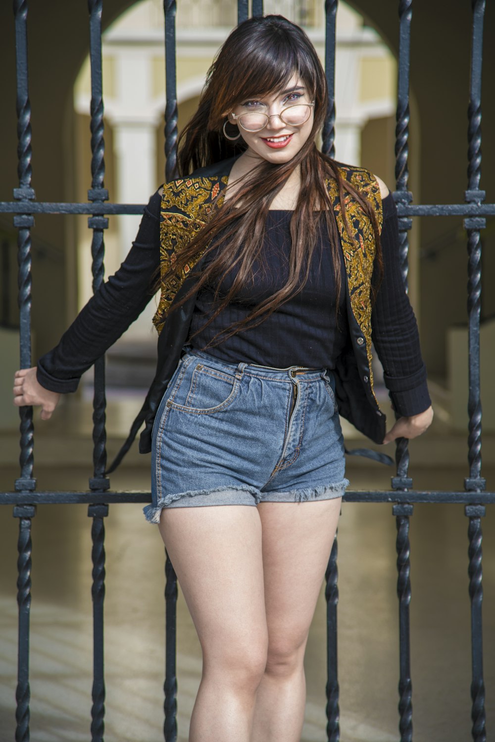 a woman is standing behind a gate with her hands on her hips