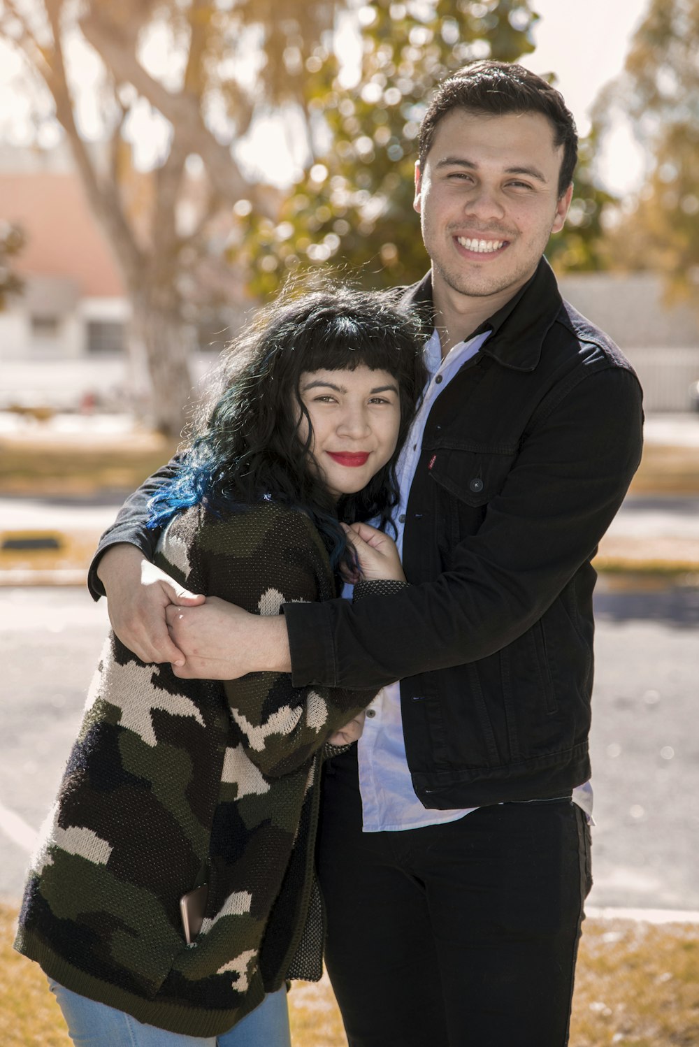 a man hugging a woman in front of a tree