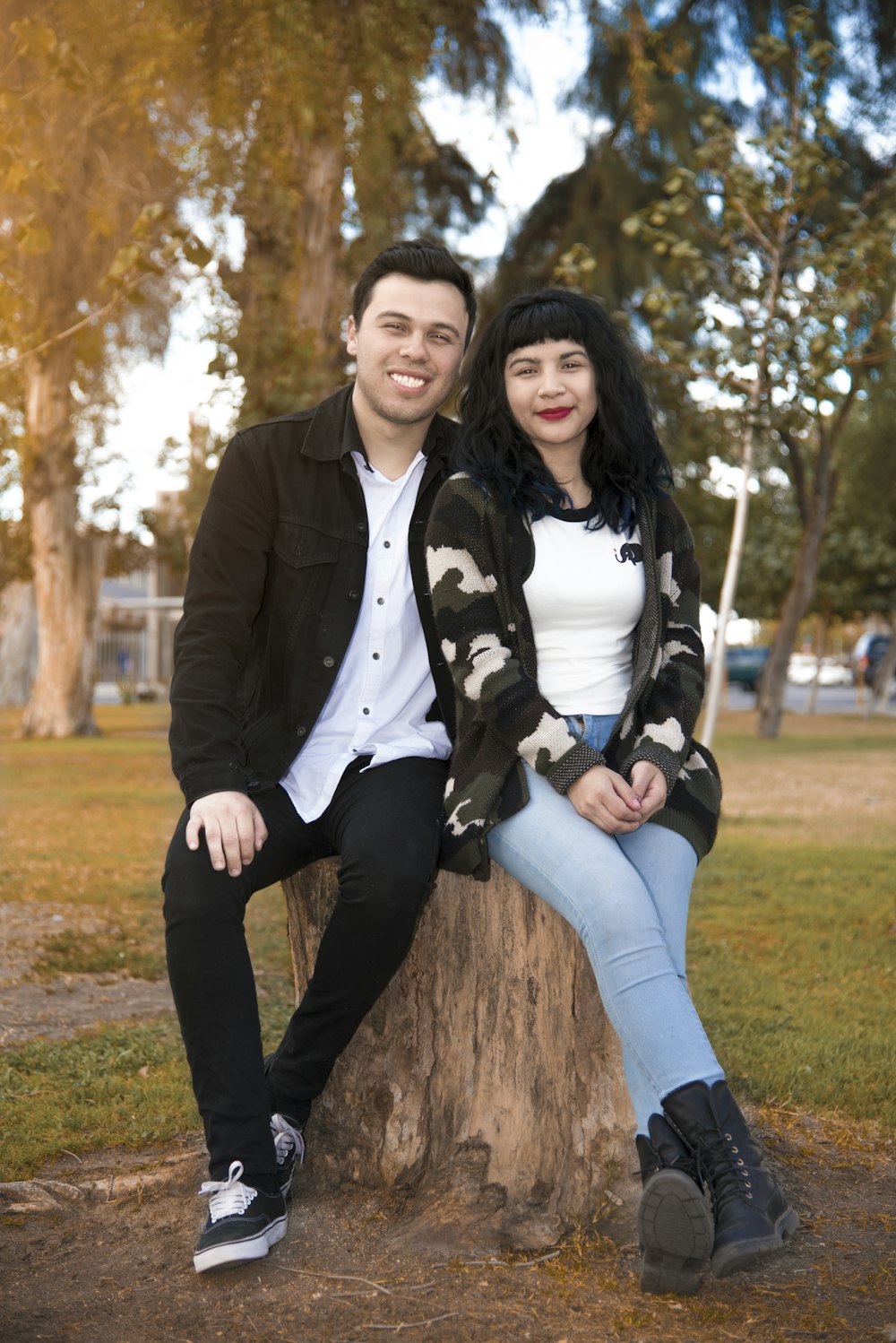 a man and a woman sitting on a tree stump