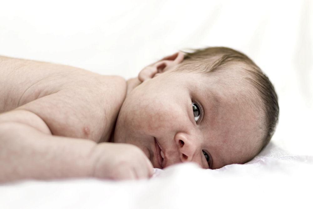 a close up of a baby laying on a bed