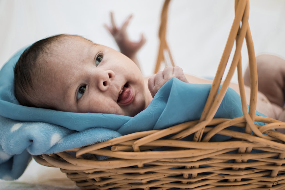 a baby wrapped in a blanket laying in a basket