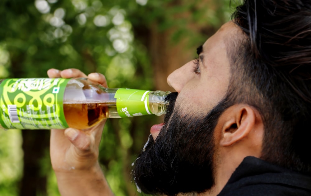 Un homme avec une barbe buvant une bière