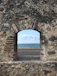 a view of the ocean through an old brick wall