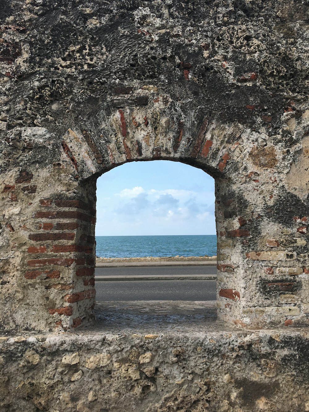 a view of the ocean through an old brick wall