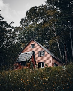 a house in the middle of a field with trees in the background