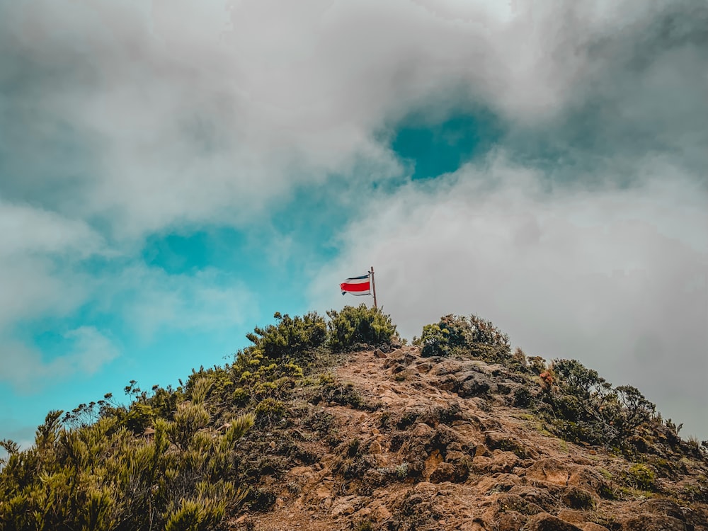 a flag on top of a hill with clouds in the background