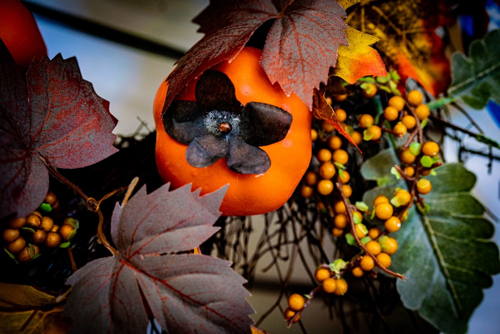 a close up of a wreath with oranges and leaves