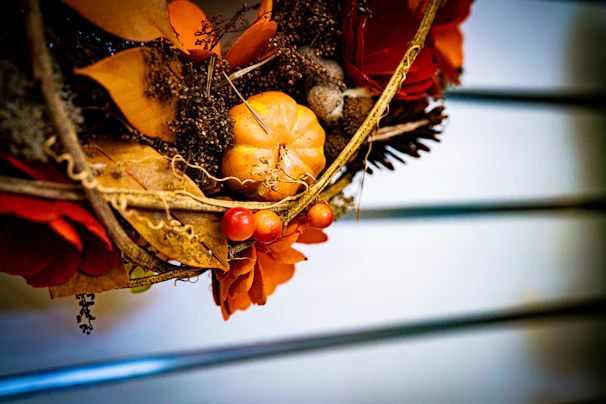 A close-up of a vibrant autumn wreath made with dried leaves, berries, and delicate flowers hanging on a rustic wooden door.