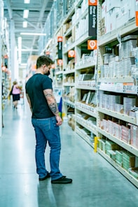 a man standing in a store aisle looking at items