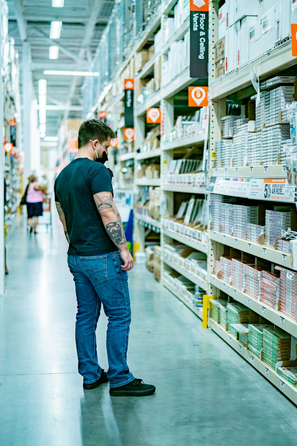 a man standing in a store aisle looking at items