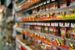 Rows of metal fittings and adapters are neatly arranged on display shelves in a store. Each item is attached to color-coded labels and price tags, giving a sense of organization and variety. The shelves extend into the background, suggesting a large selection of hardware items.