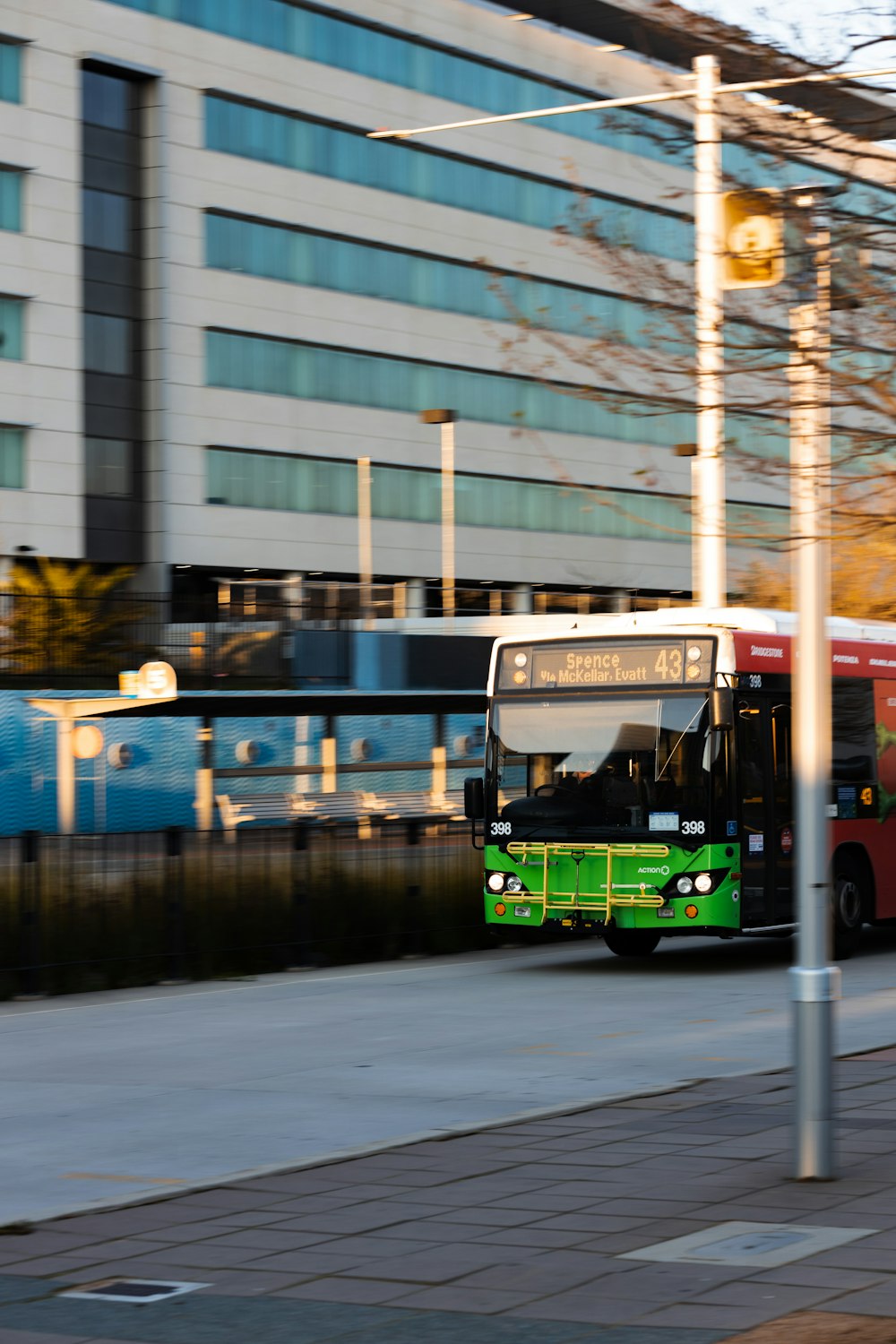 a green bus driving down a street next to a tall building