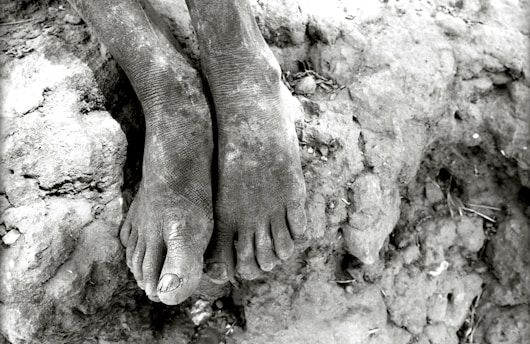 Close-up of a pair of worn barefoot aussie running shoes resting on sunlit red Australian earth.