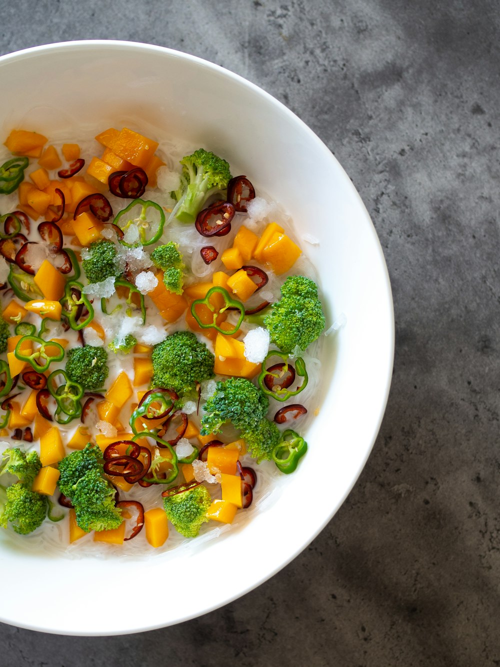 a white bowl filled with rice, broccoli and other vegetables